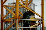 Three construction workers use tools and safety gear to maintain a building, ensuring structural integrity and functionality.