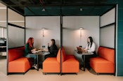 Three employees using hoteling office space with shared work areas, demonstrating flexibility and efficient space use.