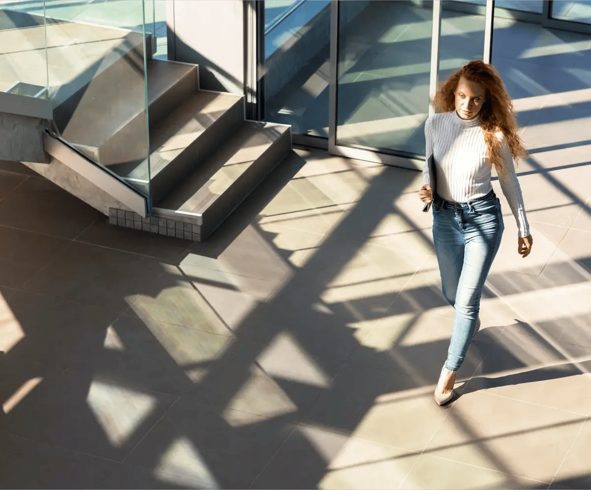 An employee walks through the office holding a report, focused on delivering important information to a colleague.