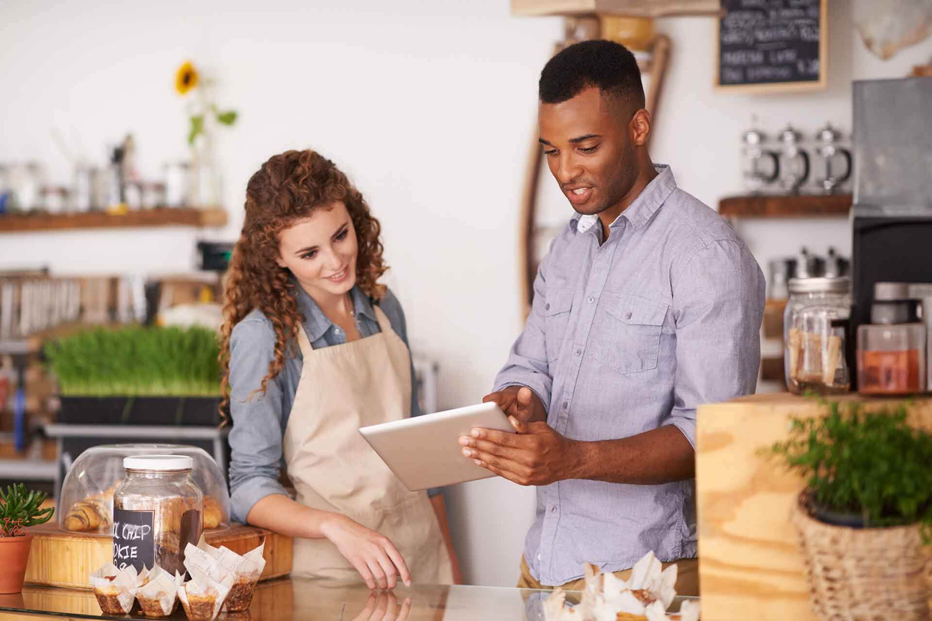 A shop owner and an employee looking at a tablet on utiizing Lx Transaction Management