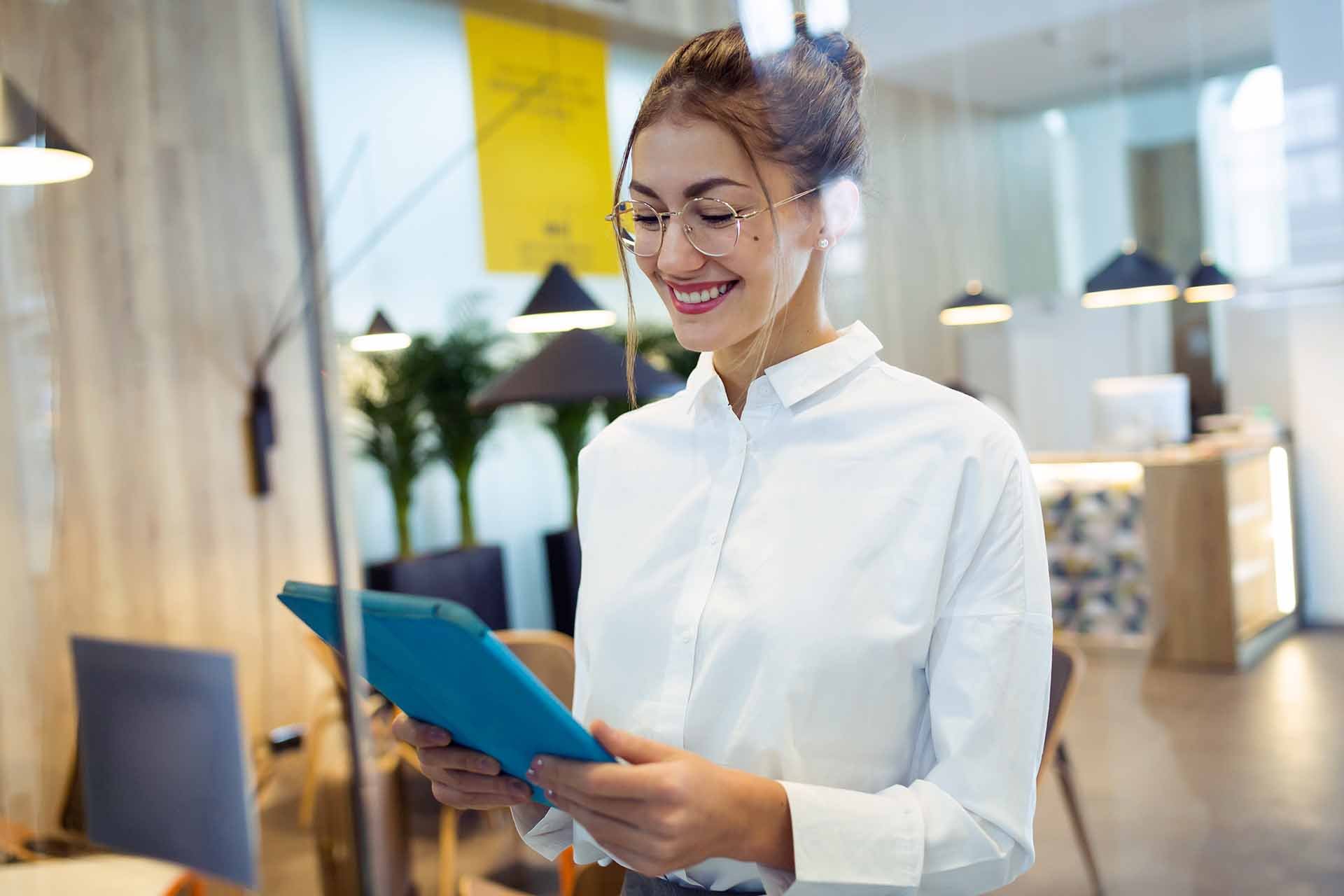 Smiling woman holding a tablet in a modern office environment