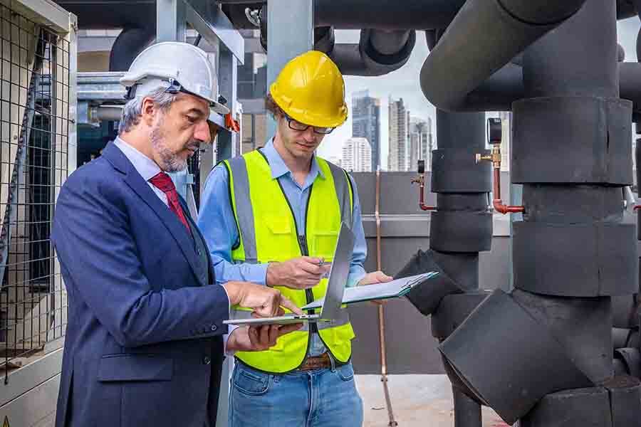 A construction worker and a manager discussing project on a table while taking notes