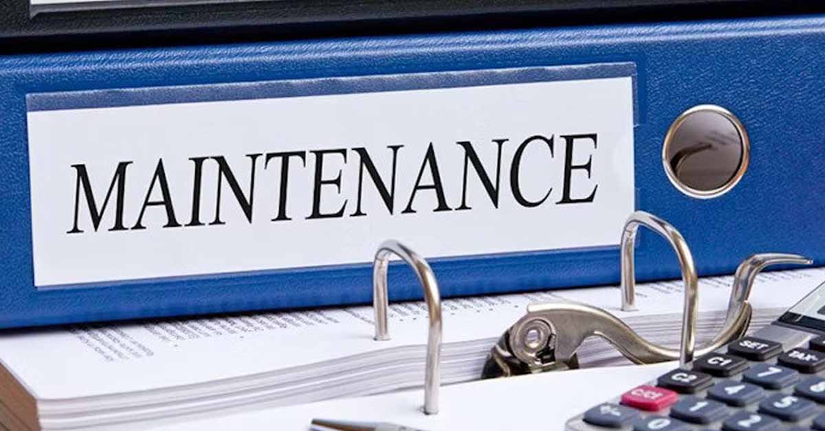 A blue binder labeled 'Maintenance' on a desk with papers, a hole puncher, and a calculator