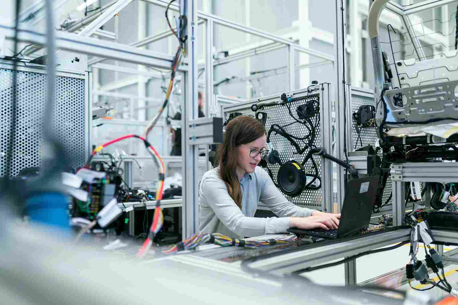 A female engineer working on a laptop in an advanced manufacturing facility