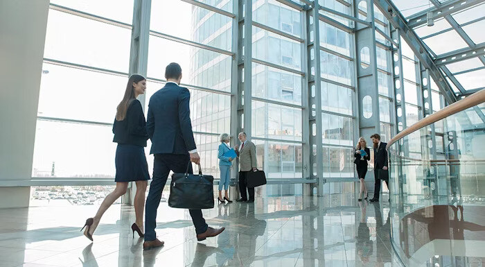 Business professionals walking and conversing in a modern glass building with large windows