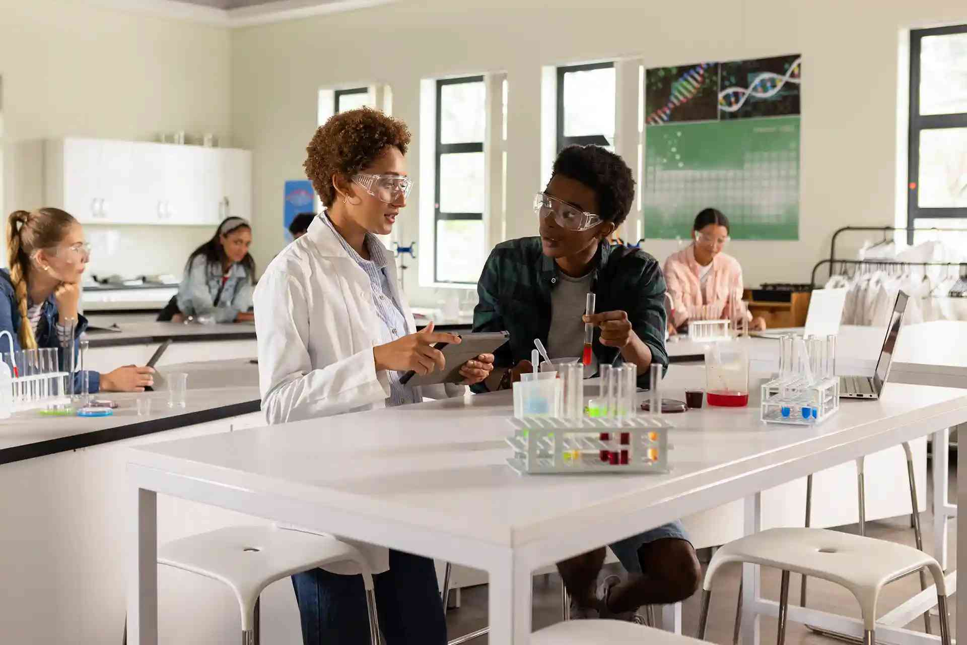 Students wearing safety goggles work together on a science experiment in a lab