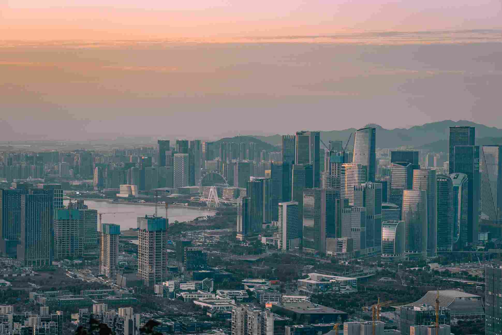 City skyline at sunset with modern skyscrapers and a ferris wheel in the background