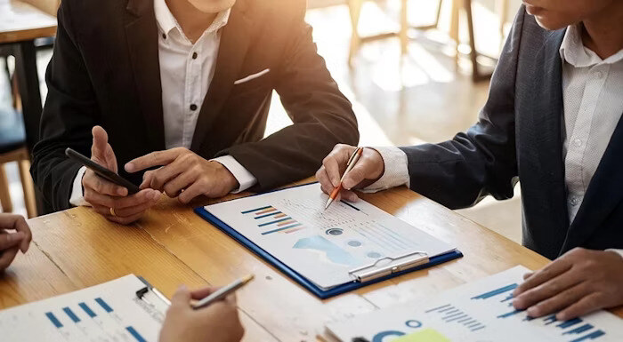 Business professionals reviewing charts and graphs on paper and a clipboard during a meeting