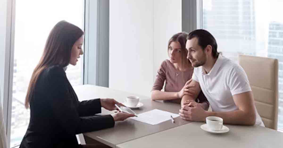 A couple meeting with a businesswoman at a table in a modern office, discussing documents