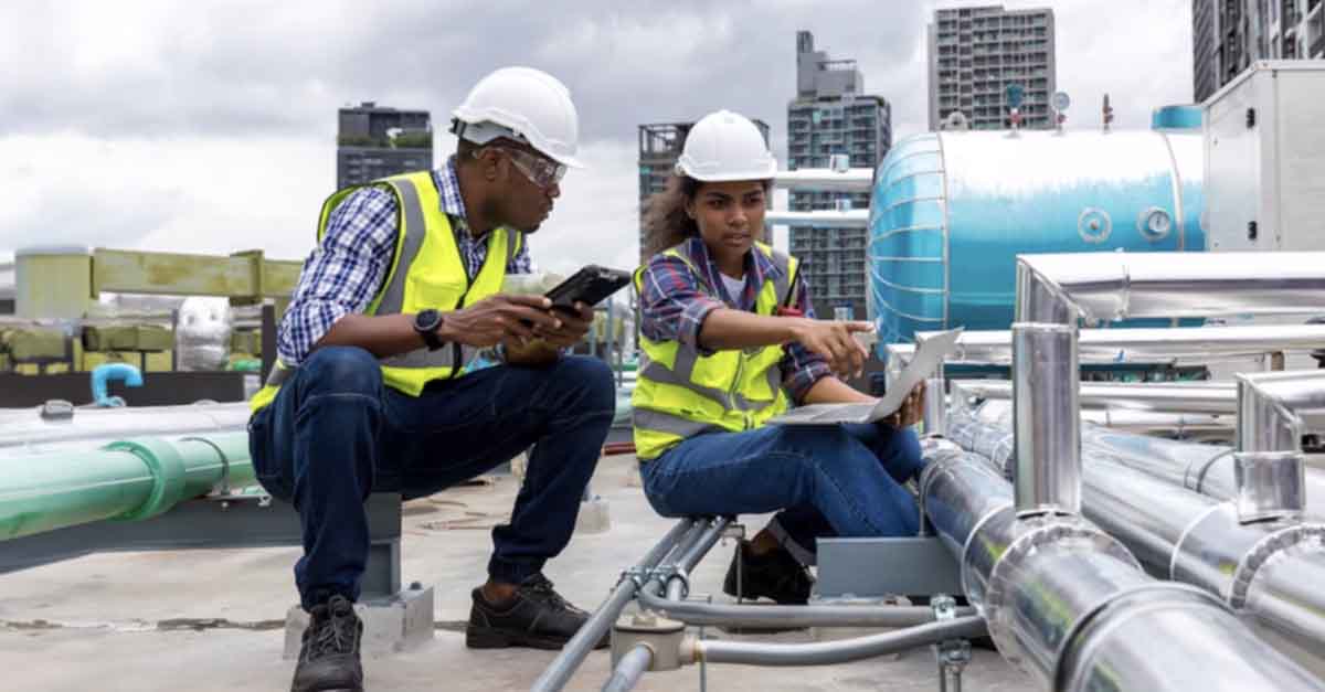 Two engineers inspecting pipes on a rooftop