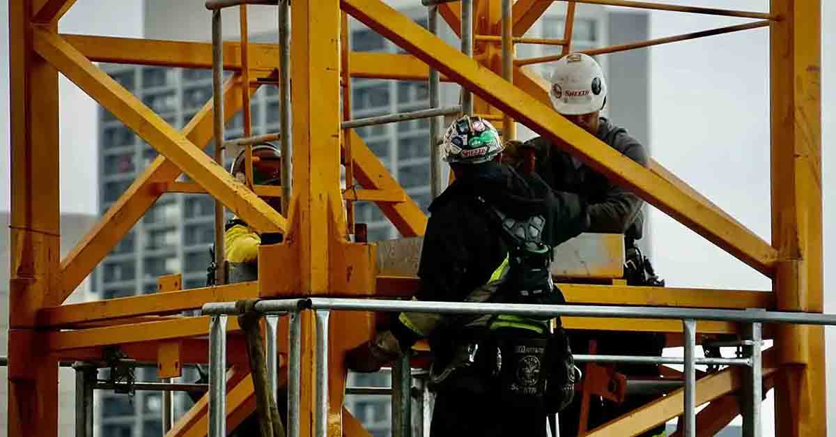 Three construction workers use tools and safety gear to maintain a building, ensuring structural integrity and functionality.