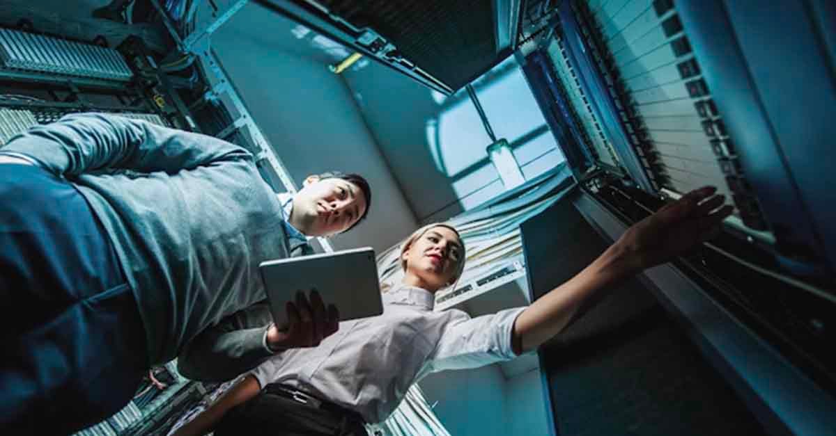 Two IT professionals working in a server room