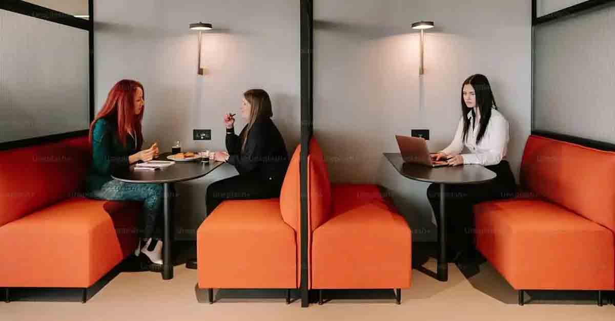 Three employees using hoteling office space with shared work areas, demonstrating flexibility and efficient space use.