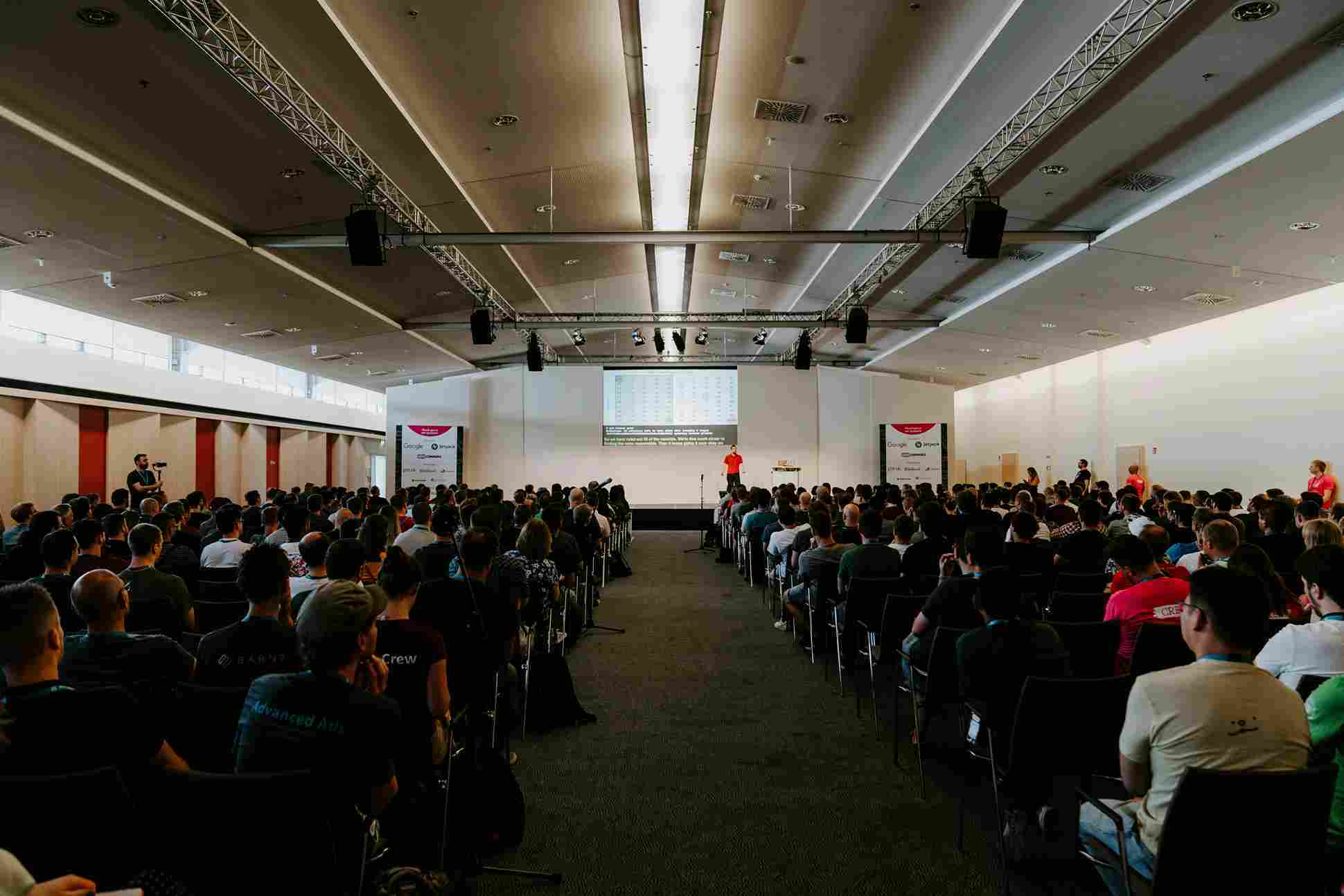 Speaker presenting to a large audience at a conference event