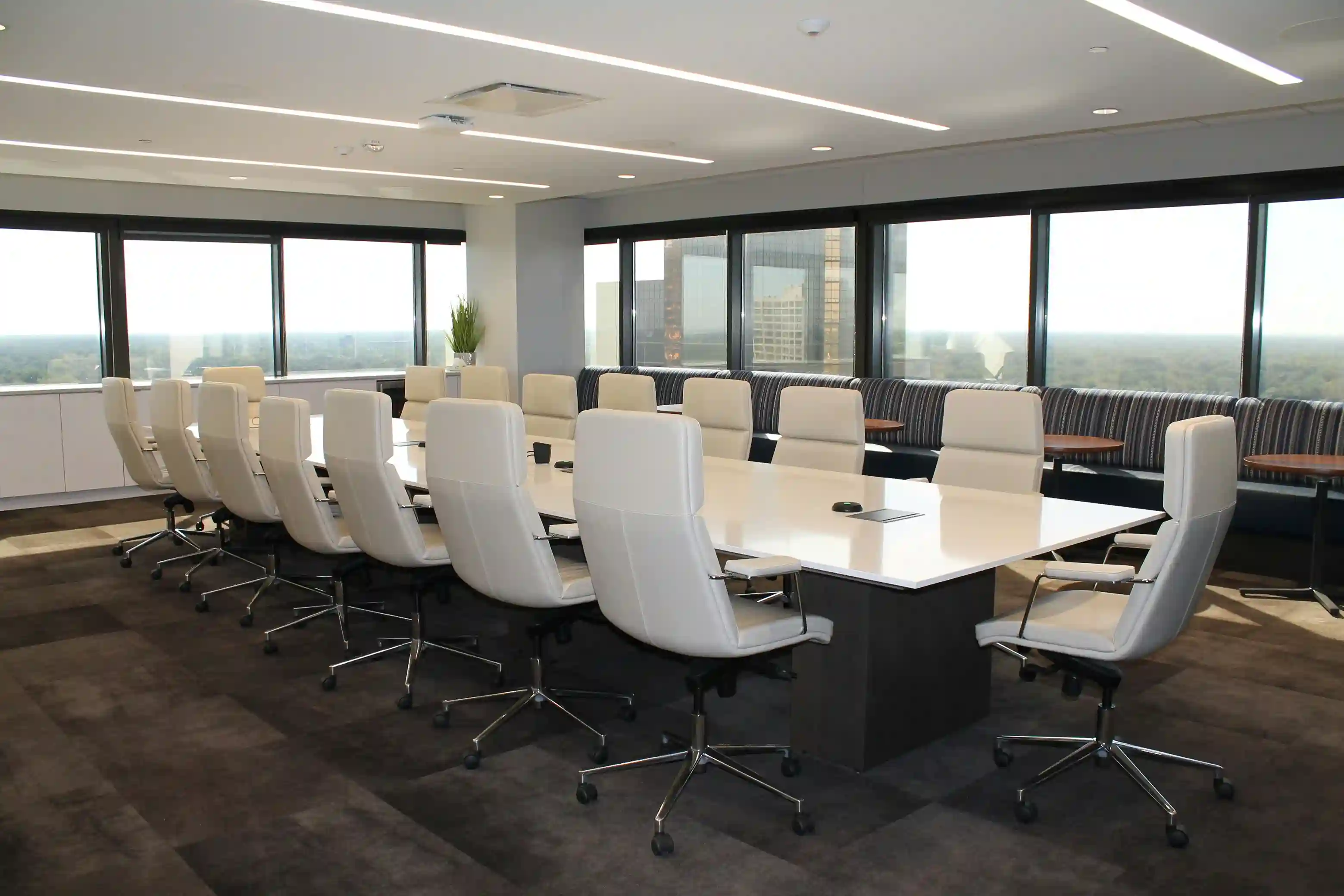 Modern conference room with a long table, white chairs, and large windows overlooking a cityscape