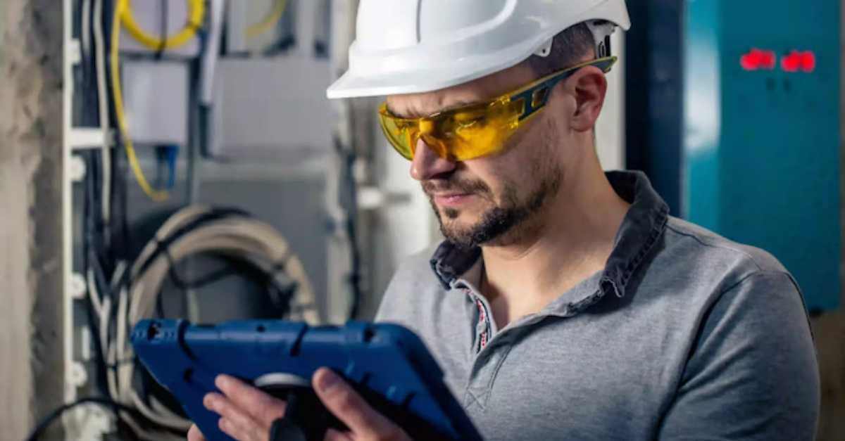 Worker using an energy management system on a tablet in an industrial setting.