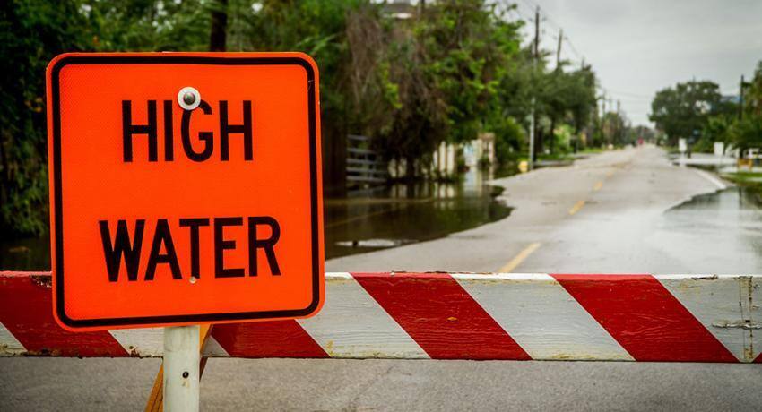 A 'High Water' warning sign blocking a flooded street