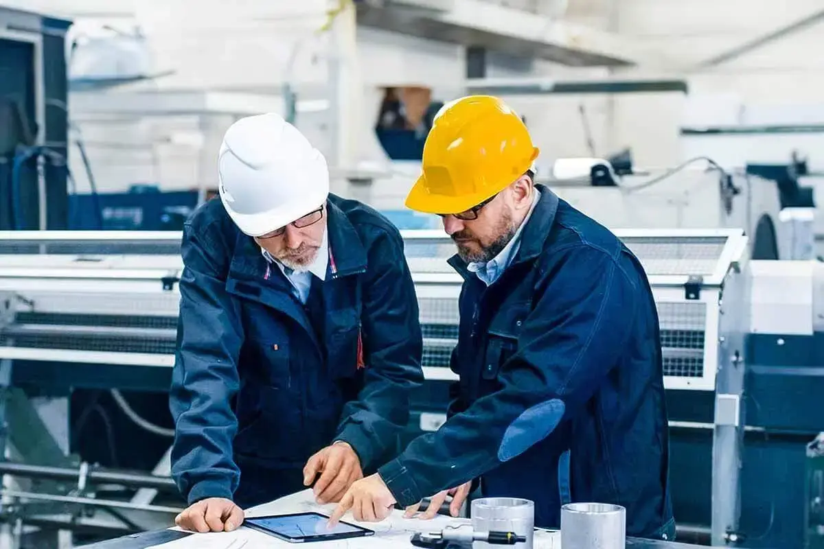 Two men with hardhats looking at tablet, utilizing Engineering document management software