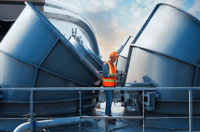 Engineer working on industrial equipment with large metal structures and pipes