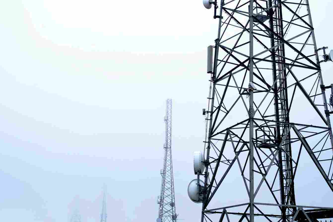 Communication towers in a foggy sky with satellite dishes attached