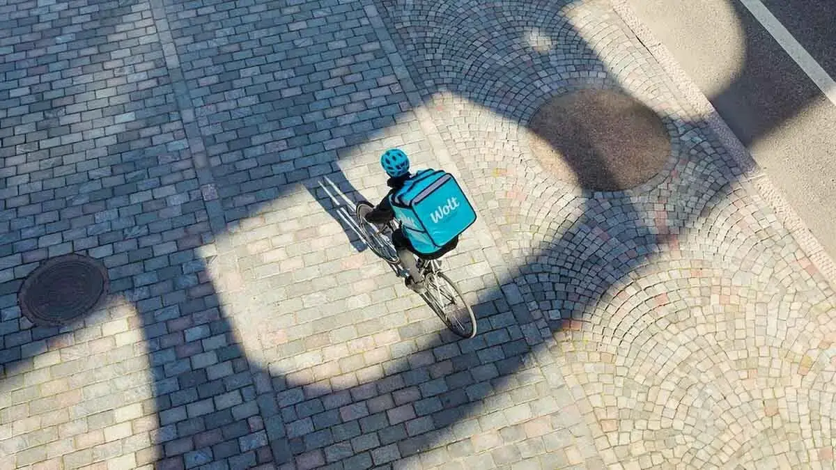 Aerial view of a Wolt delivery cyclist on a cobblestone street