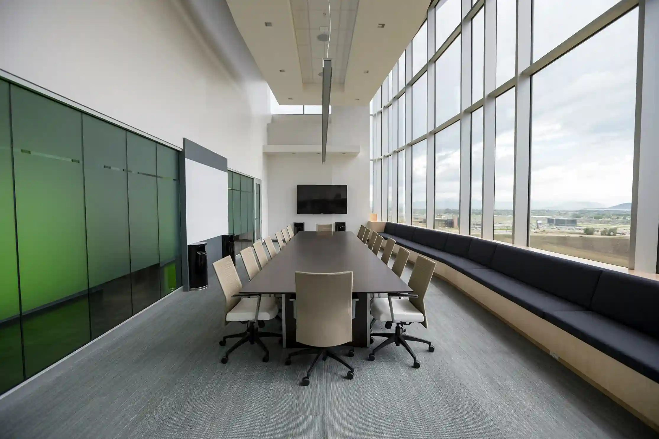 Modern conference room with a long table, chairs, and large windows overlooking a scenic view